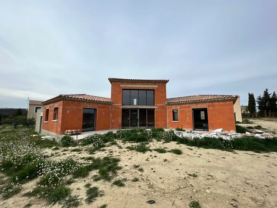 Façade principale d’une maison en brique avec grandes baies vitrées sur deux niveaux